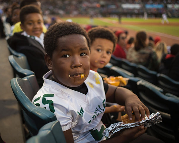 adorable young football fan eating hot dog